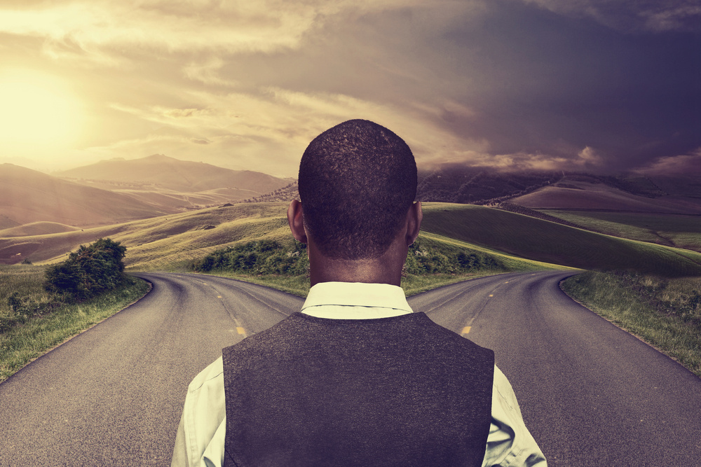 businessman in front of two roads hoping for best taking chance